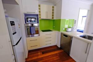 a kitchen with white cabinets and green walls at 2-Bedroom Apt with Terraces in Gold Coast