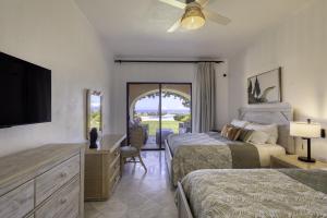 a bedroom with two beds and a dresser with a television at Beautiful Beachfront Condo With Spectacular Views in El Bedito