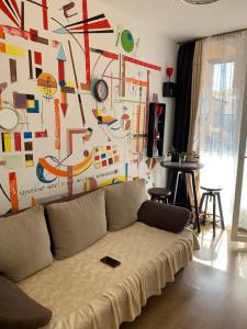 a living room with a couch in front of a wall with drawings at Sunny view South studio Мир Авангарда in Sunny Beach