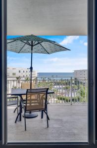 d'une table et d'un parasol sur le balcon. dans l'établissement NEW Beachfront Bliss- Sleeps 8, 2 Pools, Lazy River, à Fort Walton Beach