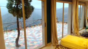a bedroom with a view of a balcony with a tree at Refuge AIT M'HAMED in Aït Mehammed
