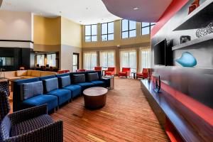 a waiting room with blue couches and red chairs at Sonesta Essential Junction City in Junction City