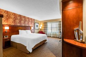 a hotel room with a large bed and a television at Sonesta Essential Junction City in Junction City