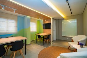 a room with two tables and chairs and a screen at Studio Completo ao Lado da PUC - CAP109 in Curitiba