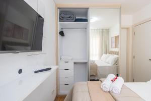 een witte slaapkamer met een bed en een televisie bij Apartamento de 1 Quarto com Sofa-Cama - CEN1104 in Curitiba