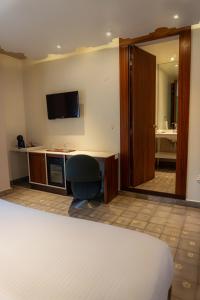 a room with a bed and a desk and a mirror at Flor de Mayo Hotel & Restaurant in Cuernavaca