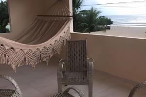 a patio with a hammock and a chair and the beach at Eficiência - Casa São Pedro - Casa Beira Mar in Camocim
