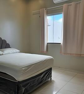 a bed sitting in a room with a window at Eficiência - Casa Vitória Régia in Camocim +11 photos