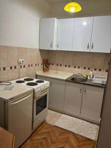 a kitchen with white cabinets and a stove and a sink at Apartman kod autobuske in Bijeljina +9 photos