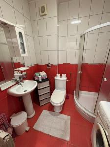 a red and white bathroom with a toilet and a sink at Apartman kod autobuske in Bijeljina
