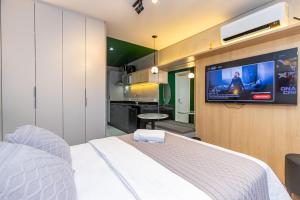 a bedroom with a bed and a tv on a wall at Studio Super Completo em Região Tranquila -EIX0202 in Curitiba