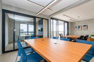 a conference room with wooden tables and blue chairs at Studio Super Completo em Região Tranquila -EIX0202 in Curitiba
