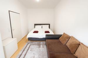 a white bedroom with a bed and a couch at Beenie MG in Linz