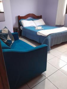 two beds and a chair in a room at Suíte em casa compartilhada a poucos metros da praia in São Sebastião