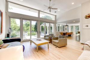 ein Wohnzimmer mit Deckenventilator und Fenstern in der Unterkunft Pathside Cove by Rove Travel - 4BR Villa with Outdoor Spaces in Wainscott