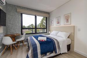 a bedroom with a bed and a table and a window at Studio Completo para 3 pessoas com A/C - EIX0302 in Curitiba +51 photos