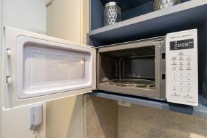 a microwave oven on a shelf in a kitchen at Studio Completo para 3 pessoas com A/C - EIX0302 in Curitiba