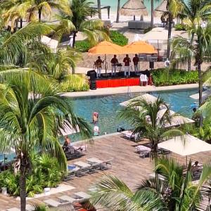 a pool with palm trees and people in a resort at Villa del Palmar in Cancún