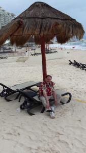 a man sitting on a bench under an umbrella on the beach at Villa del Palmar in Cancún
