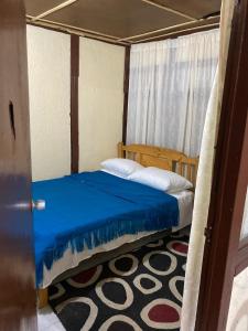 a small bedroom with a bed with a blue blanket at Cabaña Emanuel in Paipa