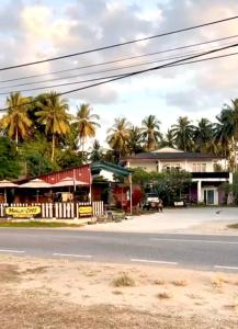 a street with houses and palm trees on the side of a road at BlackSands Guests House Langkawi in Huma