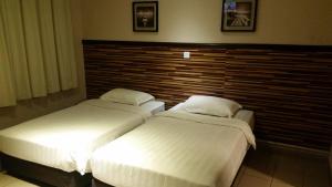 2 camas en una habitación de hotel con cabecero en Hotel Iskandar, en Kota Kinabalu