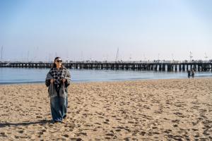a woman walking on the beach with a pier in the background at NEMO Deluxe - 3 min od plaży i parking by Lion Apartments Sopot in Sopot