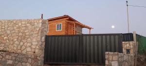 a wooden house behind a fence and a stone wall at Los Espinillos Cabaña Exclusiva in Huerta Grande