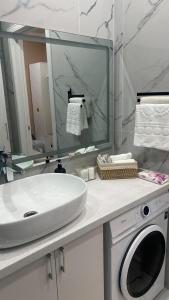 a bathroom with a sink and a washing machine at Евро двушка in Astana