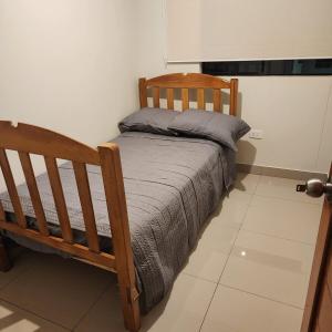une chambre avec un lit en bois avec une couverture grise dans l'établissement chiclayo, à La Victoria