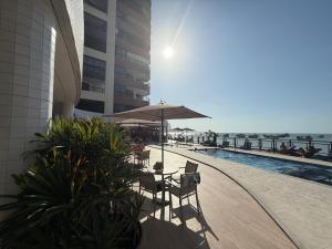 patio con sedie e ombrellone accanto alla piscina di Flat - Iate Plaza Hotel a Fortaleza