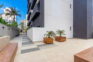 a courtyard with two palm trees on the side of a building at Studio Completo em Região Tranquila - EIX0502 in Curitiba