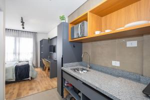 eine Küche mit einem Waschbecken und ein Zimmer mit einem Bett in der Unterkunft Studio Completo no Eixo - EIX0507 in Curitiba + 49 Fotos