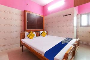 a bedroom with a bed in a room with pink walls at SPOT ON Apple Tree Cottage in Palani
