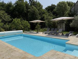 een zwembad met stoelen en parasols in een tuin bij Les Gîtes de La Pellerie - 2 piscines intérieur & extérieur - Touraine - 3 gîtes - familial, calme, campagne in Saint-Branchs