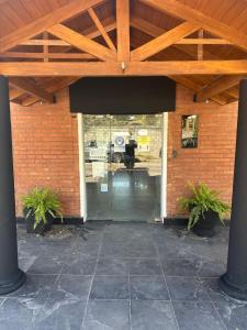 een open deur naar een bakstenen gebouw met twee potplanten bij Hotel en villa carlos paz centrico con desayuno y pileta Nuevo Enzo in Villa Carlos Paz