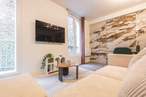 a living room with a couch and a tv on a wall at L'Étape 4 - Center - Cathedral in Reims