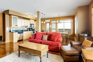 a living room with a red couch and a kitchen at Glacier Lodge 106 in Big White