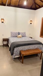 a bedroom with a large bed with a bench on it at Riquezas de Lavras Novas - Chalé Safira in Lavras Novas
