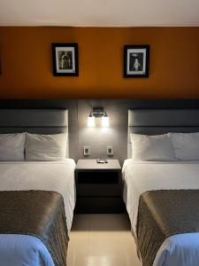 a hotel room with two beds and a table between them at Hotel El Rancho in Sabinas Hidalgo