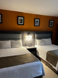a hotel room with two beds and two pictures on the wall at Hotel El Rancho in Sabinas Hidalgo