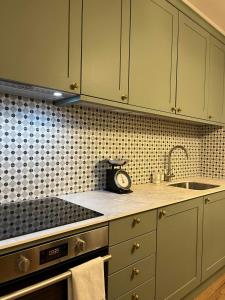 eine Küche mit grünen Schränken und einer Uhr auf der Theke in der Unterkunft Victorian Inspired Home in Stockport + 3 Fotos