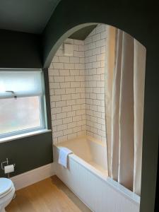 a bathroom with a bath tub and a toilet at Victorian Inspired Home in Stockport