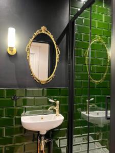 a green tiled bathroom with a sink and a mirror at Victorian Inspired Home in Stockport +3 photos
