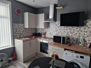 a kitchen with white cabinets and a tv on the wall at Stella Lounge Bradford West Yorkshire UK in Idle