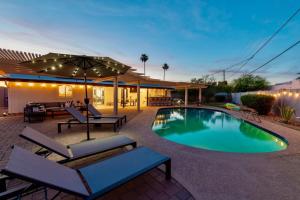 a swimming pool with chairs and an umbrella at Massive Backyard - Pool, Hot Tub, Putting Green, & Fire Pit in Tempe