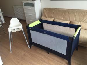 Cette chambre comprend un petit lit et une chaise haute. dans l'établissement Résidence Sparrow, à Coxyde