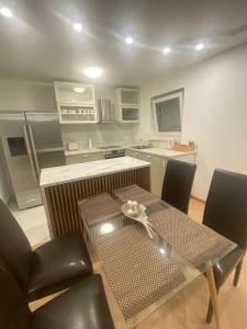 una cocina con mesa de cristal y sillas y una cocina con encimera. en MiA Apartment, en Bad Herrenalb