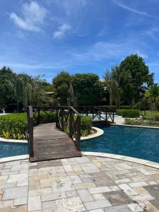 eine Holzbrücke neben einem Schwimmbecken in der Unterkunft Apartamento no resort in Barra de São Miguel