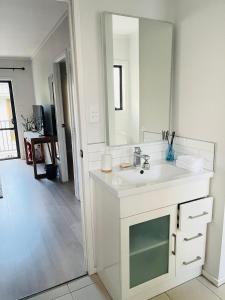 un bagno bianco con lavandino e specchio di Sunny Tidy Corner in Ellerslie ad Auckland